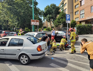 Na zdjęciu strażacy przeprowadzający akcje ratowniczą. Obok osoby postronne robiące zdjęcia.