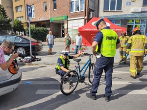 Na zdjęciu policjanci. Jeden z nich trzyma rower. Obok nich osoby postronne.