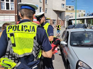 Na zdjęciu dwóch umundurowanych policjantów podczas symulacji zdarzenia drogowego.