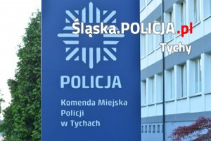 Logo Komendy Miejskiej Policji w Tychach na tle budynku.