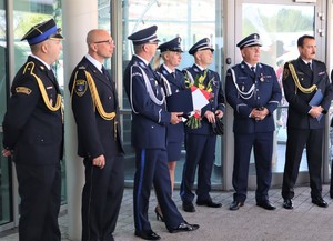 Na zdjęciu umundurowani policjanci oraz strażacy stojący przed budynkiem.