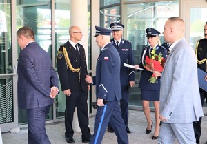 Na zdjęciu umundurowani policjanci oraz strażacy stojący przed budynkiem.