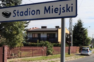 Na zdjęciu drogowskaz z napisem Stadion Miejski. W tle policyjny radiowóz.