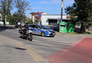 Na zdjęciu policyjny radiowóz i motocykl podczas zabezpieczenia przemarszu kibiców.