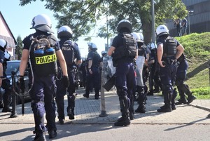 Na zdjęciu umundurowani policjanci z oddziałów prewencji podczas przemarszu kibiców na stadion.