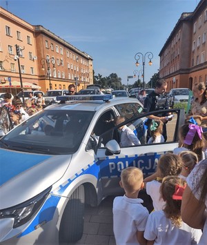 Na zdjęciu policyjny radiowóz, policjanci i dzieci.