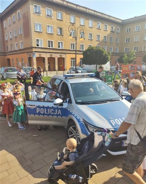 Na zdjęciu policyjny radiowóz, policjanci i uczestnicy pikniku.
