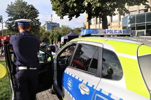 Na zdjęciu policjant ruchu drogowego stojący przy radiowozie.