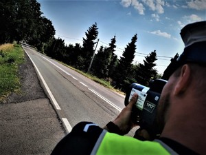 Na zdjęciu policjant ruchu drogowego wykonujący pomiar prędkości.