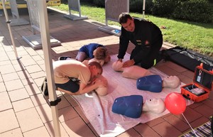 Na zdjęciu strażak i dzieci podczas ćwiczeń pierwszej pomocy przy fantomach.