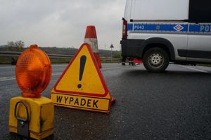 Na zdjęciu policyjny radiowóz oraz postawiony na drodze znak ostrzegawczy z napisem Wypadek.