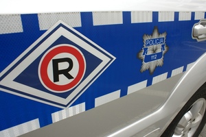 Na zdjęciu bok radiowozu policyjnego z logo wydziału ruchu drogowego oraz logo Policji