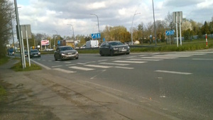 Na zdjęciu dwa samochody znajdujące się przed przejściem dla pieszych.