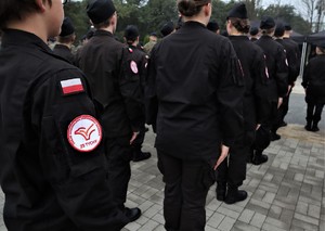 Na zdjęciu stojący tyłem uczniowie klasy mundurowej.