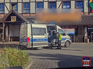 Na zdjęciu radiowóz i stojący obok niego umundurowany policjant ruchu drogowego.
