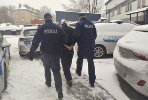 Umundurowani policjanci prowadzący zatrzymanego