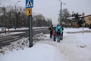 Na zdjęciu umundurowany policjant, strażnicy miejscy oraz Mikołaj podczas rozdawania odblasków.