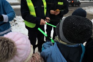 Na zdjęciu umundurowany policjant  podczas rozdawania odblasków.