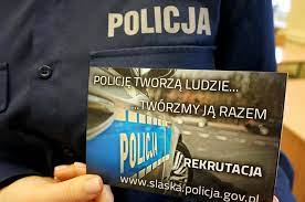 Na zdjęciu policjant trzymający ulotkę dotyczącą rekrutacji w Policji