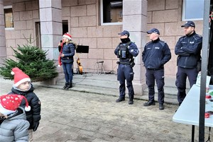 Na zdjęciu umundurowani policjanci oraz kobieta w czapce Mikołaja podczas osiedlowego pikniku.