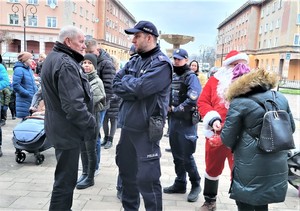 Na zdjęciu umundurowany policjant rozmawiający z mężczyzną.