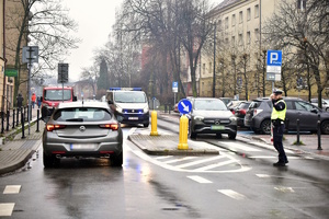 Zdjęcie przedstawia policjanta oraz policyjne radiowozy podczas orszaku Trzech Króli w Tychach.