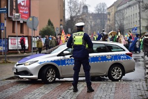 Zdjęcie przedstawia policjanta oraz policyjny radiowóz podczas orszaku Trzech Króli w Tychach.