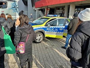 Na zdjęciu radiowóz policyjny oraz osoby biorące udział w wydarzeniu.