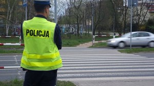 Na zdjęciu umundurowany policjant stojący w pobliżu przejścia dla pieszych.