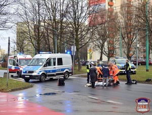 Na zdjęciu policyjny radiowóz oraz karetka oraz policjanci o ratownicy podczas udzielania pomocy poszkodowanemu w zdarzeniu drogowym.