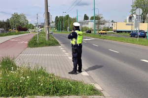 Policjant ruchu drogowego sprawdzający prędkość kierujących laserowym miernikiem prędkości.