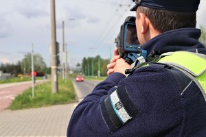 Policjant ruchu drogowego sprawdzający prędkość kierujących laserowym miernikiem prędkości.