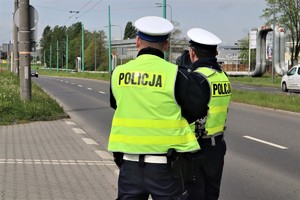 Policjanci ruchu drogowego sprawdzający prędkość kierujących laserowym miernikiem prędkości.