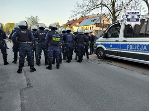 Na zdjęciu umundurowani policjanci oraz radiowozy podczas zabezpieczenia meczu piłki nożnej.