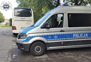 Na zdjęciu radiowóz policyjny zaparkowany obok autokaru.