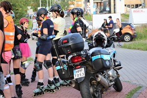 na zdjęciu osoby na rolkach stojące przy motocyklu