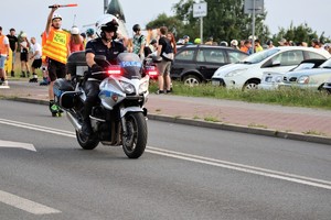 na zdjęciu policjant na motocyklu oraz osoby jadące na rolkach