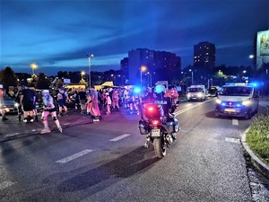 na zdjęciu policjant na motocyklu oraz osoby jadące na rolkach