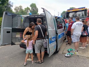 Dzieci oraz dorośli obok radiowozu