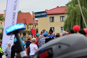 Na zdjęciu sygnał na motocyklu nadający światło barwy niebieskiej, w tle ludzie oraz tabliczka z nazwą Ronda Fundacji WOŚP.