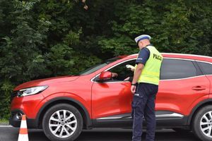 Na zdjęciu umundurowany policjant ruchu drogowego przy samochodzie osobowym.