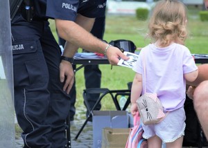 Na zdjęciu policjant wręczający kolorowankę.