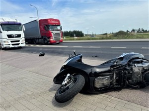 Na zdjęciu motocykl przewrócony na bok. W tle inne samochody.