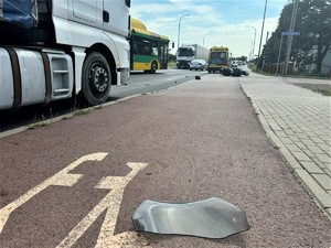 Na zdjęciu motocykl przewrócony na bok, karetka oraz inne samochody jadące drogą.