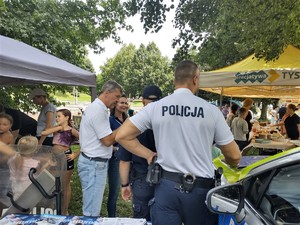 Na zdjęciu umundurowani policjanci stojący obok radiowozu oraz organizatorzy wydarzenia.