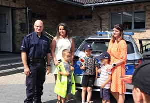 Na zdjęciu umundurowany policjant pozujący do zdjęcia z dziećmi oraz dwoma kobietami.