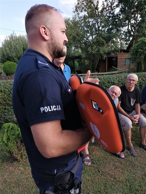 Na zdjęciu policjant trzymający AED i uczestnicy debaty.