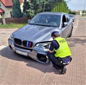 Na zdjęciu policjant przy uszkodzonym samochodzie.