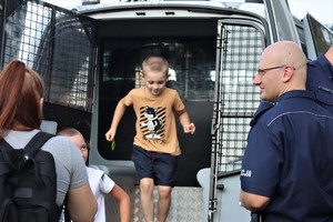 Na zdjęciu umundurowany policjant i chłopiec w radiowozie.