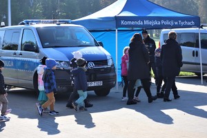 Na zdjęciu dzieci przechodzące obok oznakowanego radiowozu Policji.